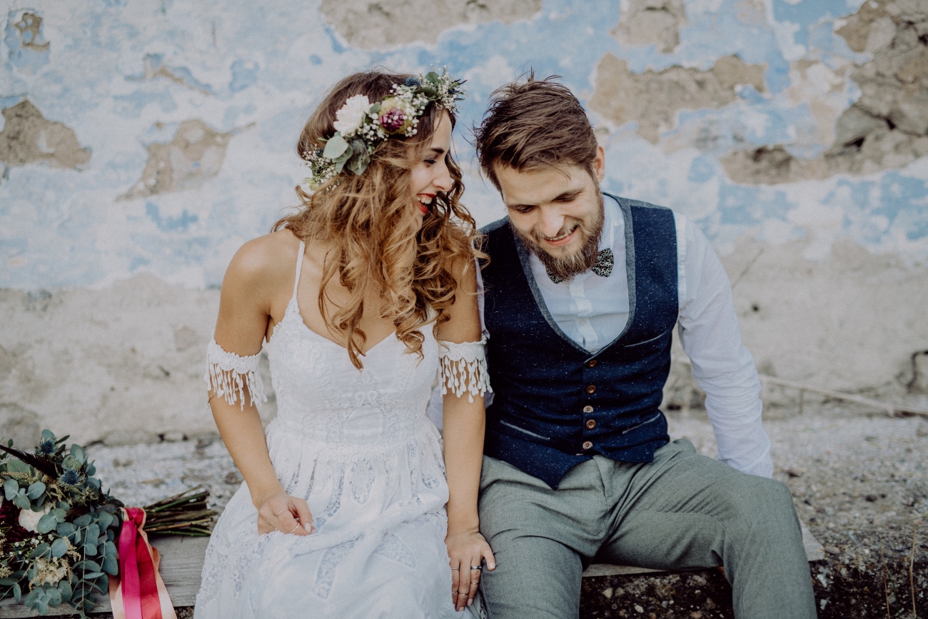 Beautiful young bride and groom outside in front of an old shabby house.